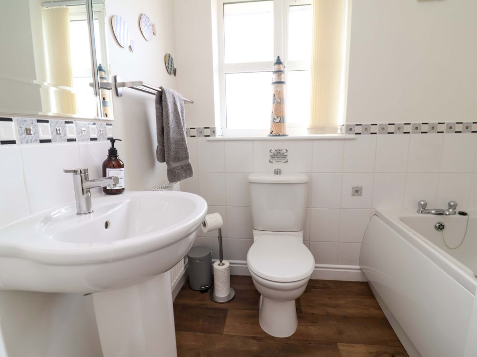 A bathroom with a sink, toilet, and bath at The Beach Escape in Prestatyn