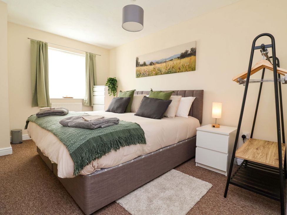 A bedroom with a bed, nightstand, and wardrobe at The Beach Escape in Prestatyn