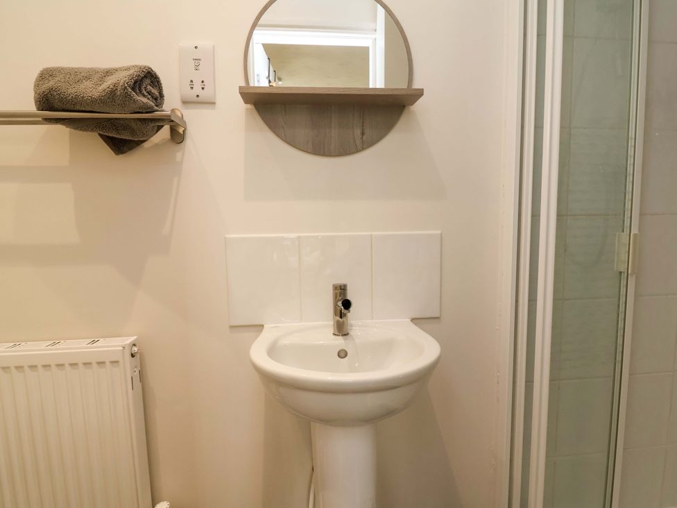 A bathroom with a sink and towel on the shelf at The Beach Escape in Prestatyn