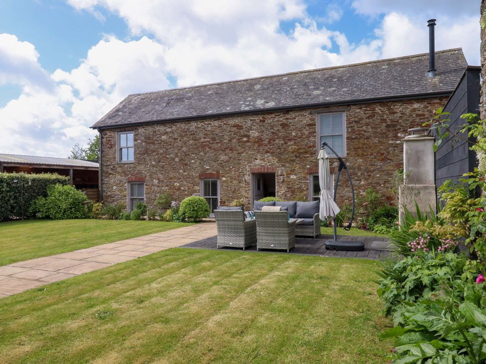 A garden with outdoor furniture and a stone house at Duke's Barn in Blackawton near Dartmouth