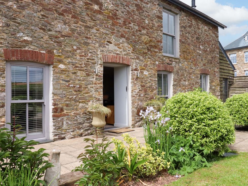 An outdoor view of a stone building with windows and a door at Duke's Barn Blackawton near Dartmouth