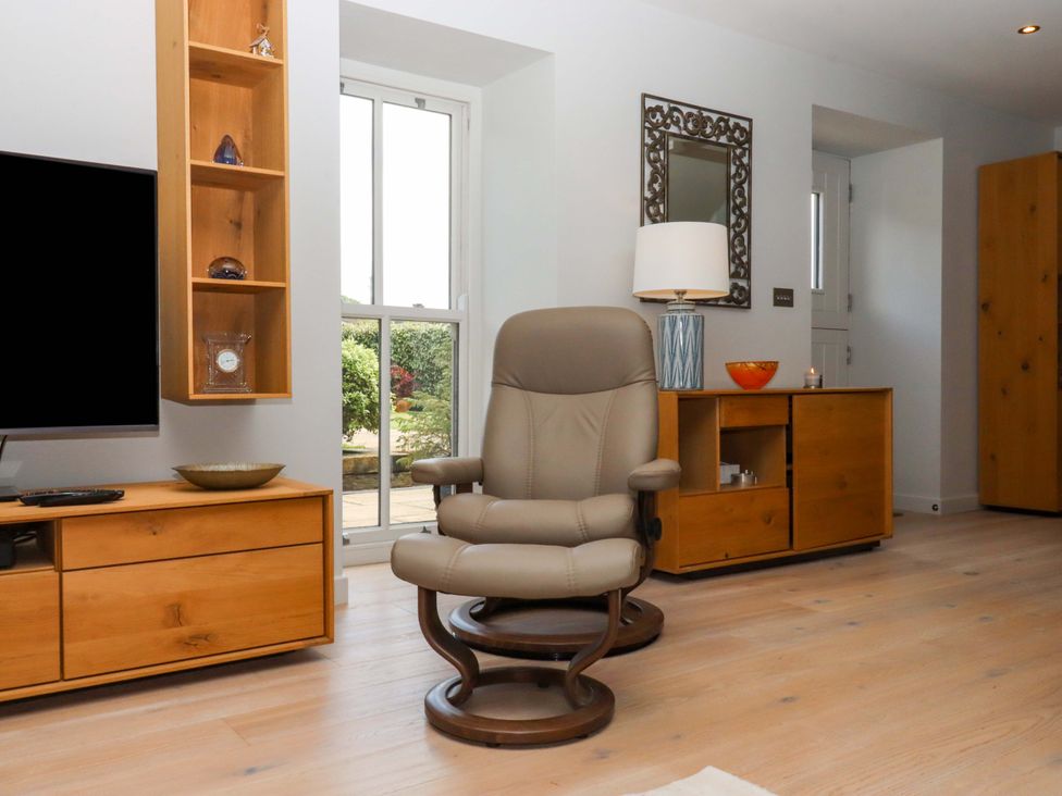 A living room with a chair and television at Duke's Barn in Blackawton near Dartmouth