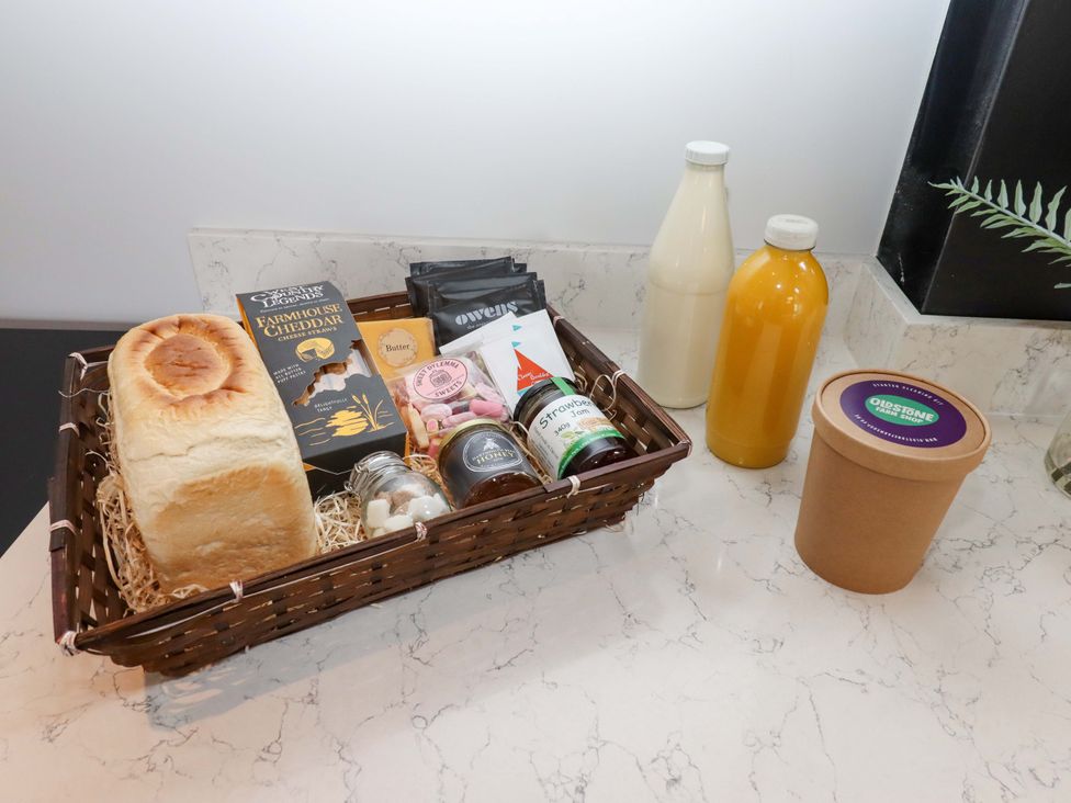 A basket with bread, cheese, butter, sweets, jam, and drinks on a countertop at Duke's Barn in Blackawton near Dartmouth