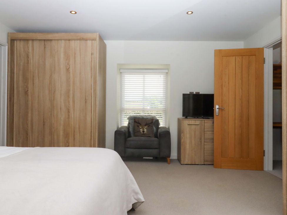 A bedroom with a bed, wardrobe, armchair and television at Duke's Barn Blackawton near Dartmouth