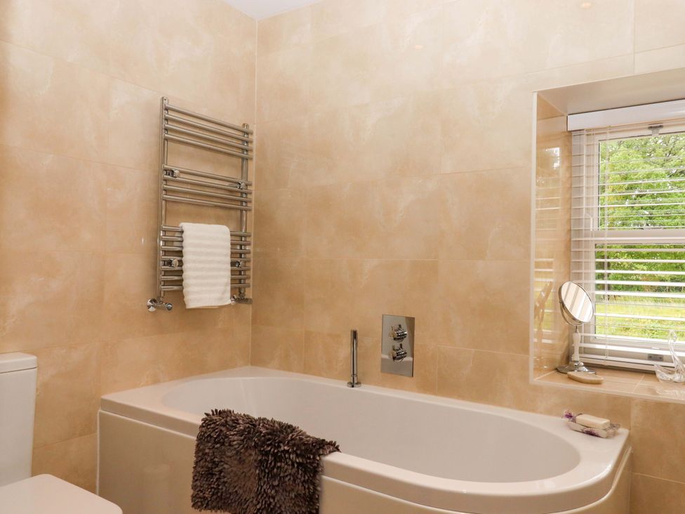 A bathroom with a bathtub and towel rail at Duke's Barn Blackawton near Dartmouth