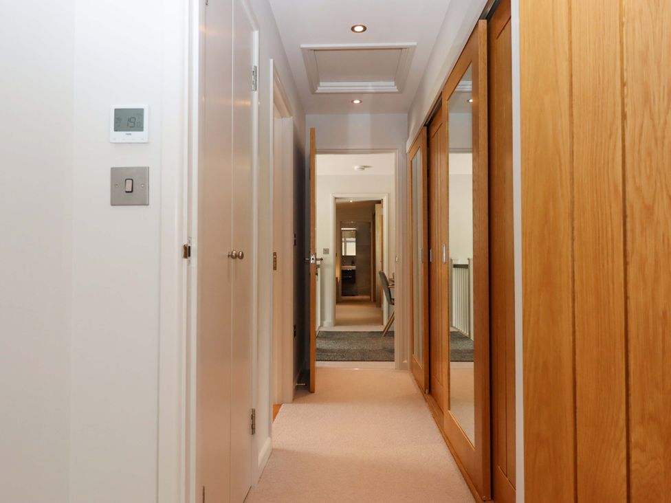 A hallway with a thermostat and mirrored wardrobe at Duke's Barn in Blackawton near Dartmouth