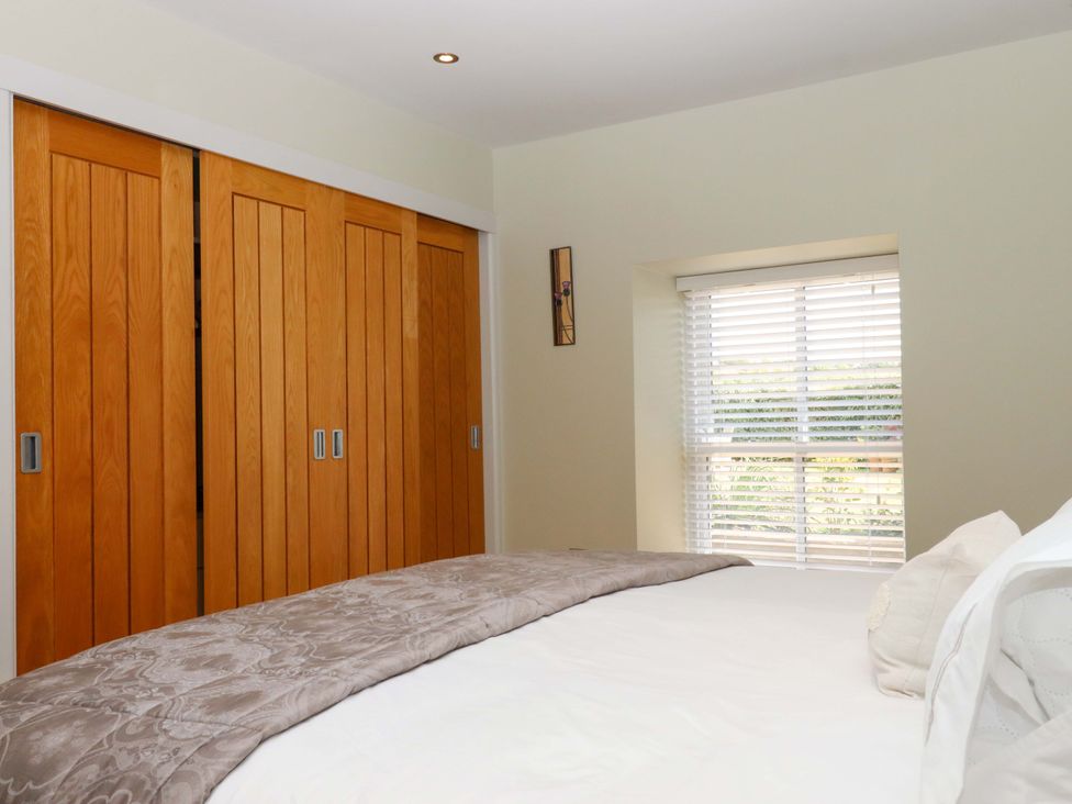 A bedroom with a bed and closet doors at Duke's Barn in Blackawton near Dartmouth