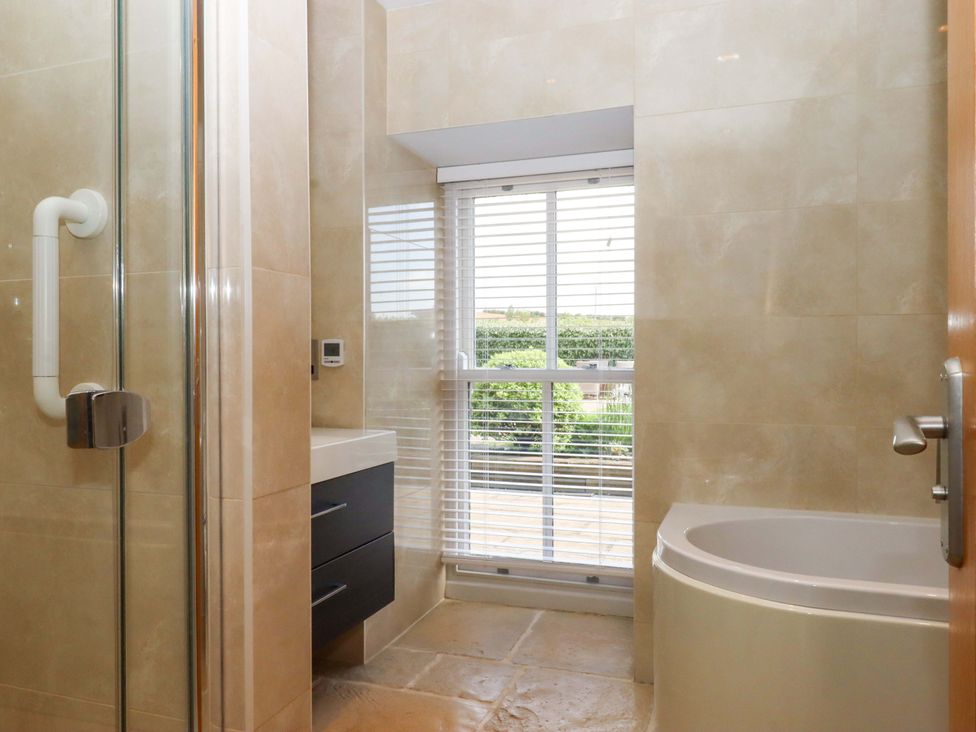 A bathroom with a shower, bathtub, sink and window at Duke's Barn Blackawton near Dartmouth