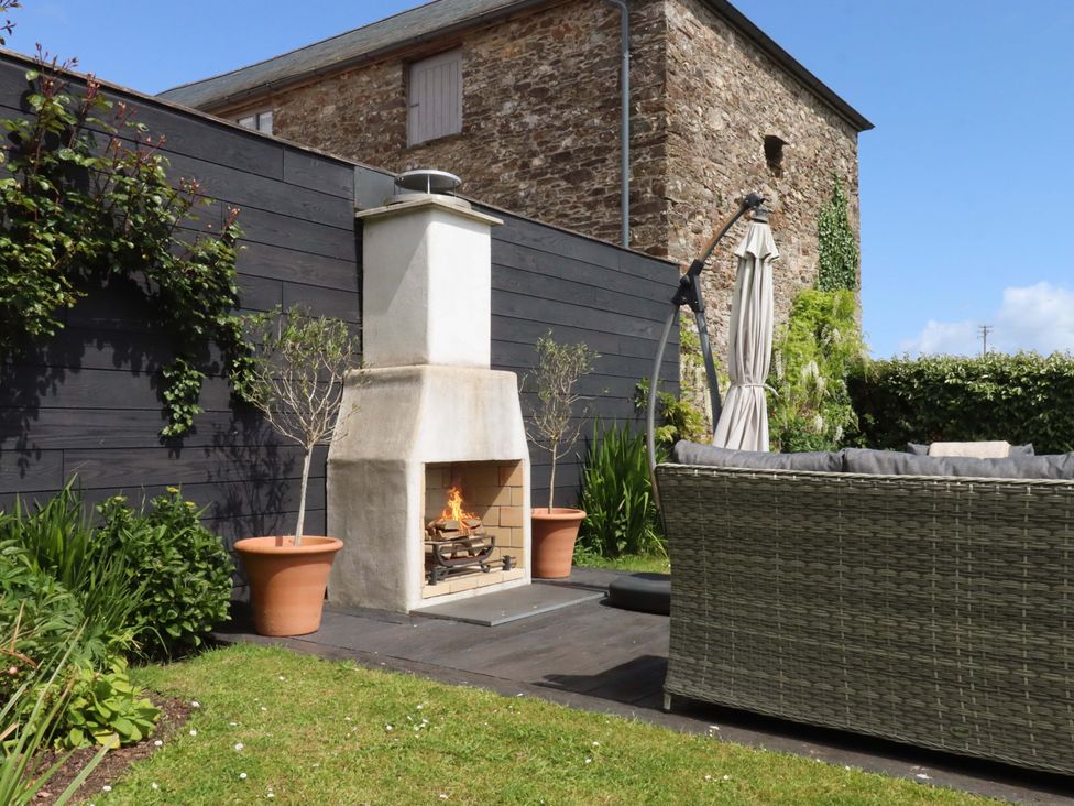 A garden with a fireplace and a couch at Duke's Barn in Blackawton near Dartmouth