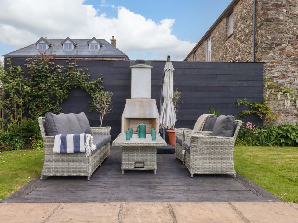 A garden area with outdoor sofas and a fireplace at Duke's Barn Blackawton near Dartmouth