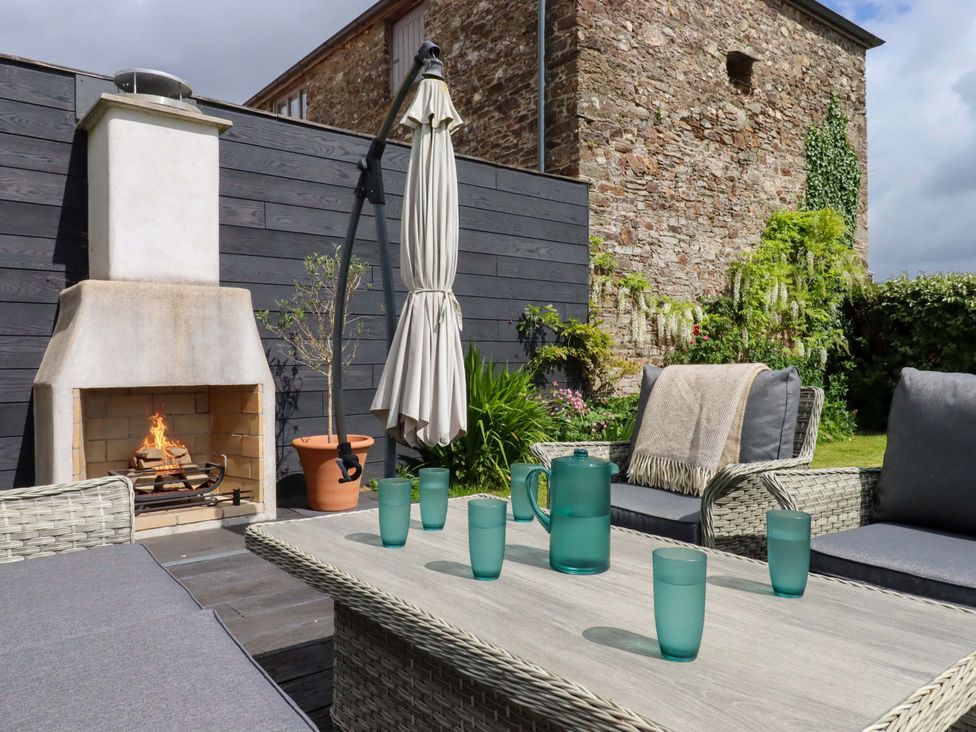 A garden with an outdoor fireplace and seating arrangement at Duke's Barn Blackawton near Dartmouth