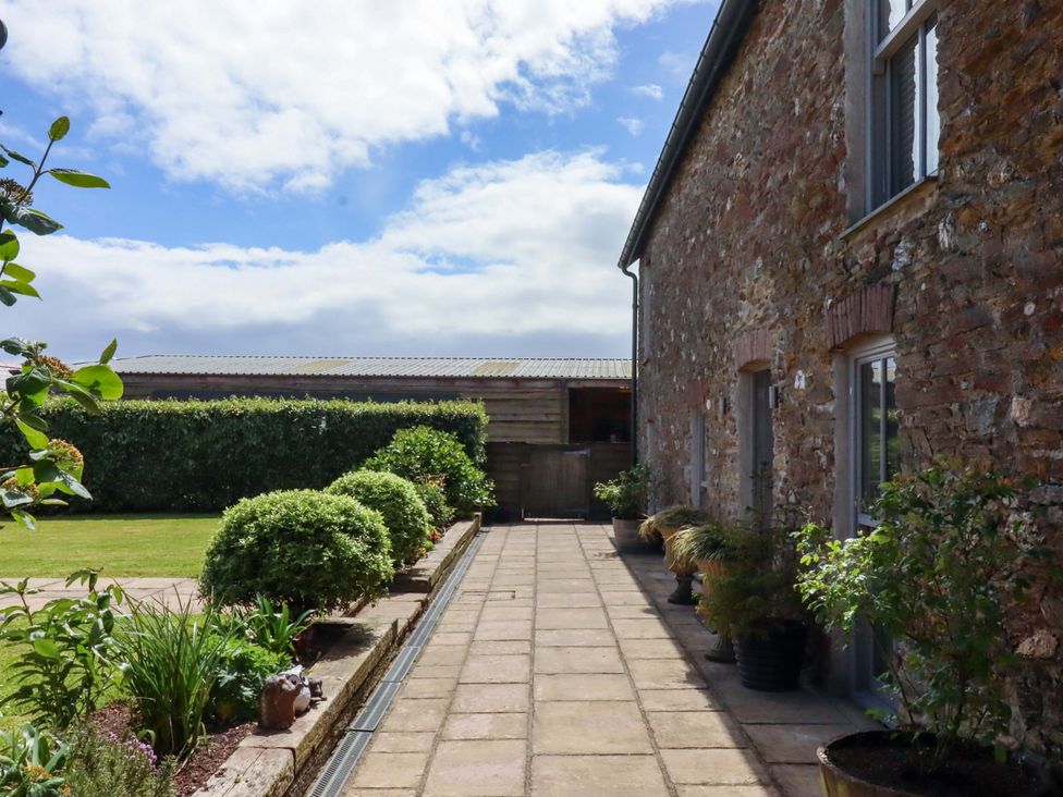 A pathway beside a stone building with planters at Duke's Barn Blackawton near Dartmouth