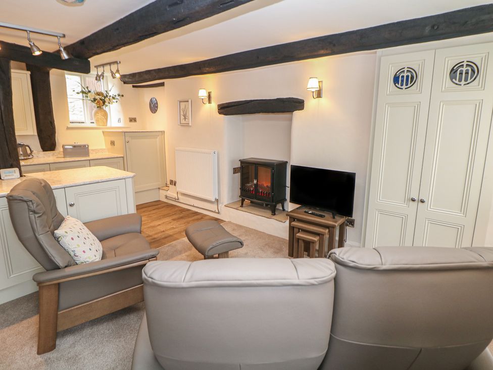 A living room with a recliner chair and electric fireplace at The Toll Bar in Hope Valley