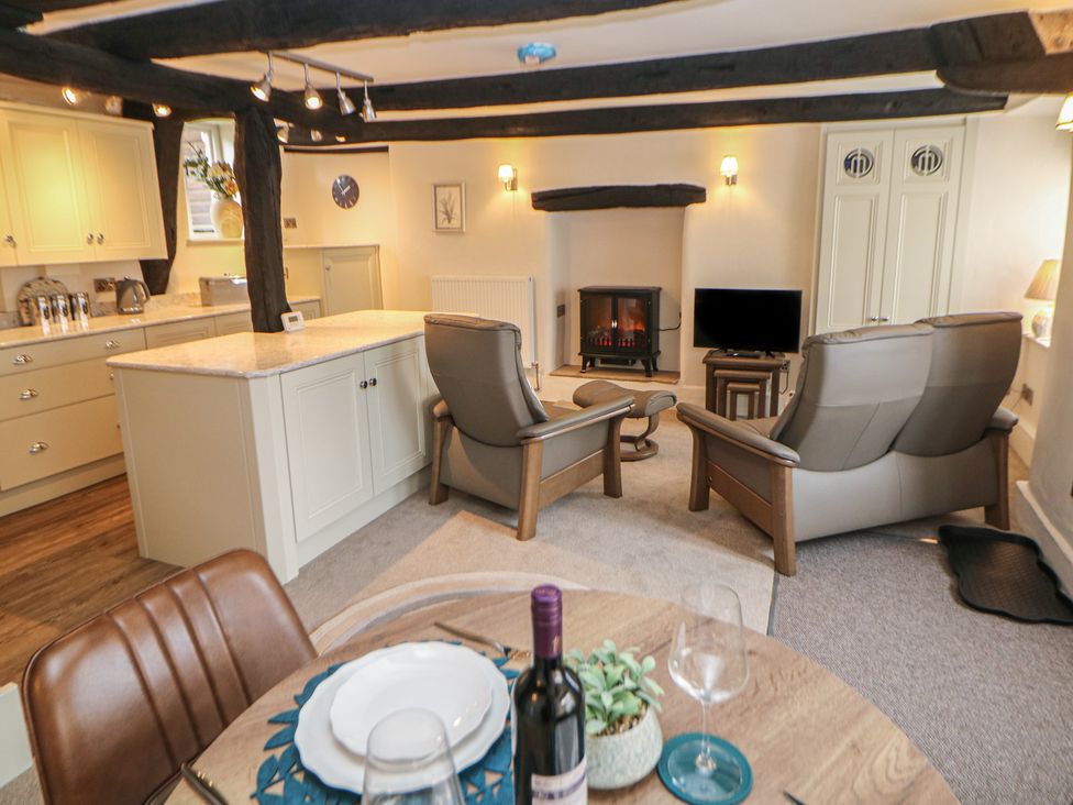 A living room with kitchen area, dining table, and seating at The Toll Bar in Hope Valley