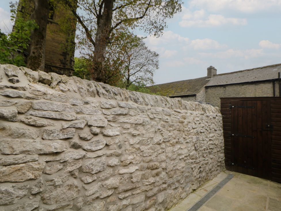 A garden view with a stone wall and a wooden gate at The Toll Bar in Hope Valley