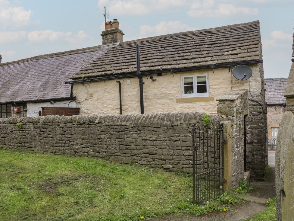 An outdoor view of a cottage with a stone wall and gate at The Toll Bar in Hope Valley