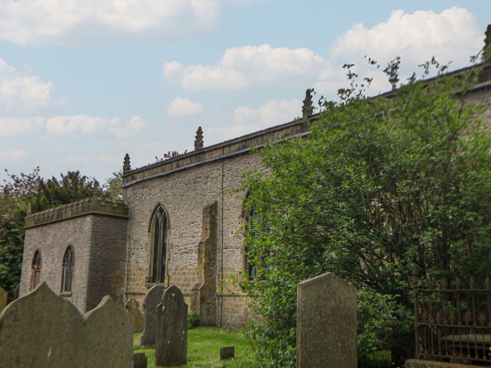 A church with gravestones and trees at The Toll Bar in Hope Valley
