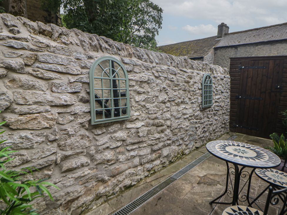 An outdoor area with a stone wall and a table at The Toll Bar in Castleton, Peak District