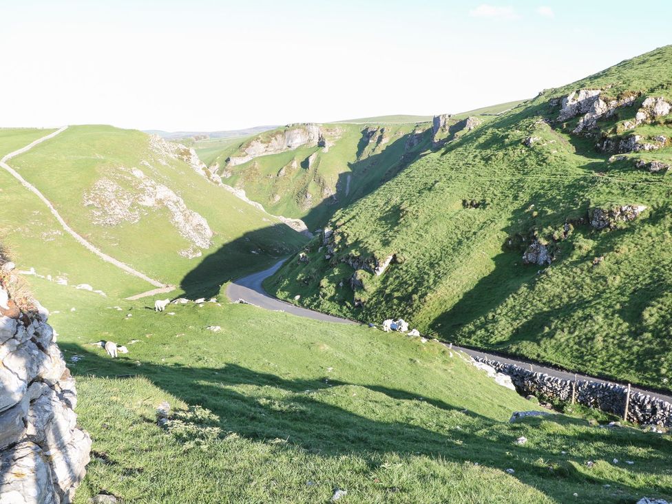 A view of a road and grassy hills with sheep at The Toll Bar in Castleton, Peak District