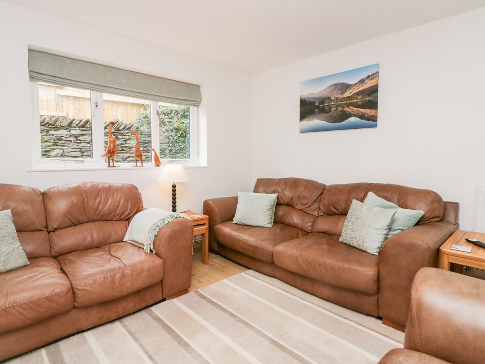 A living room with two leather sofas and a lamp at Catbells in Windermere