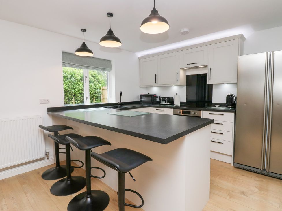 A kitchen with an island, stools, and appliances at Catbells in Windermere