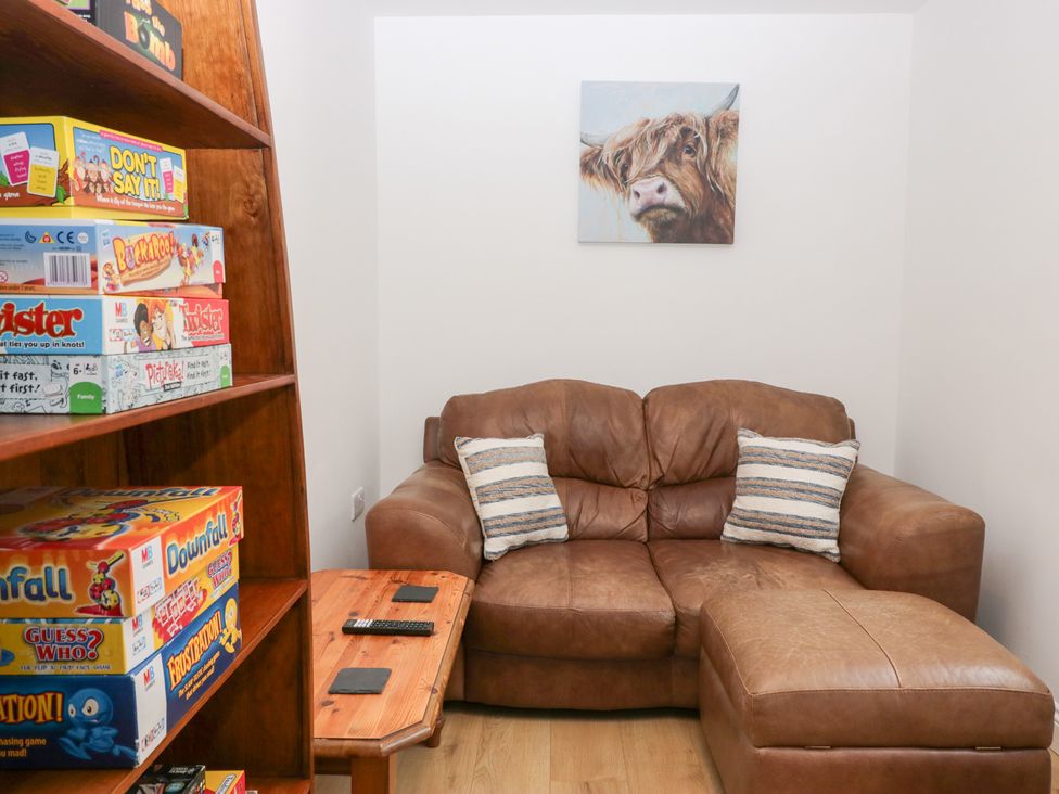 A snug with a sofa and board games on a shelf at Catbells in Windermere