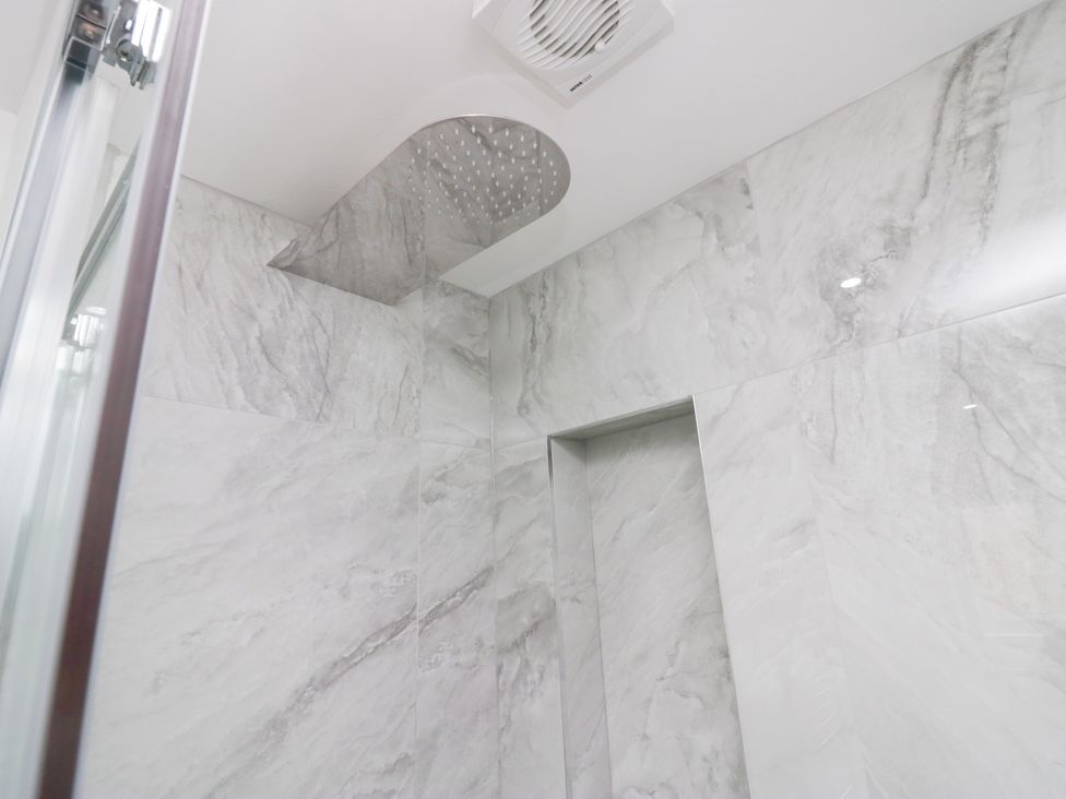 A bathroom with a shower and tiled walls at Catbells, Windermere