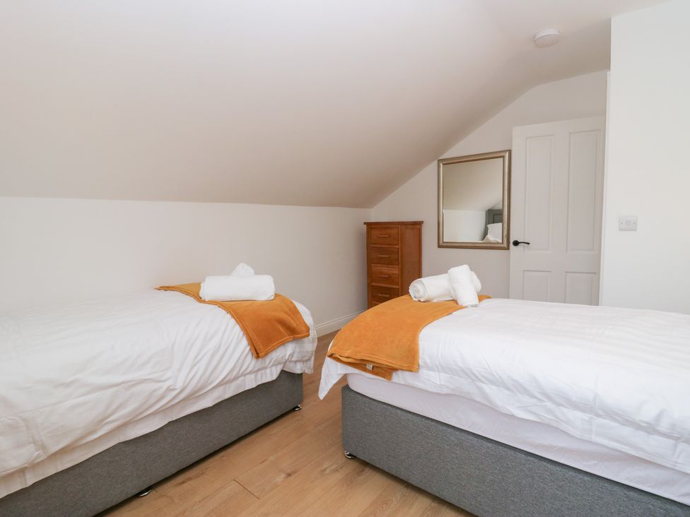 A bedroom with two beds and a wardrobe at Catbells in Windermere