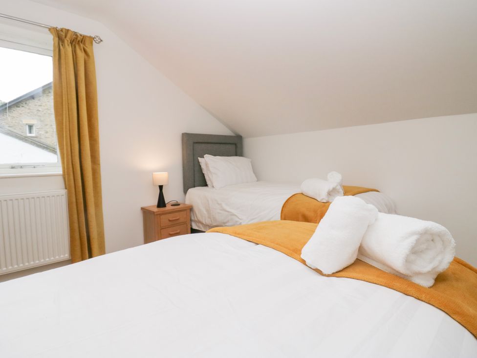 A bedroom with two beds and a lamp on a nightstand at Catbells in Windermere