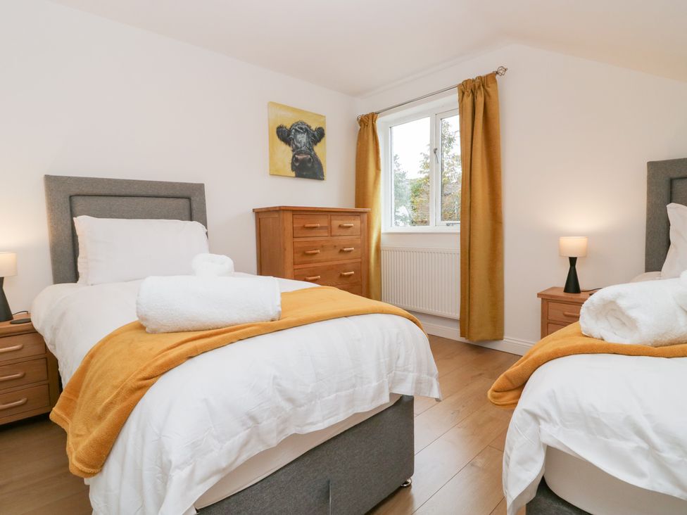 A bedroom with two beds and a chest of drawers at Catbells in Windermere