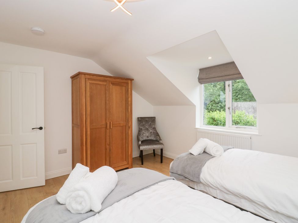 A bedroom with two beds and a wardrobe at Catbells Windermere