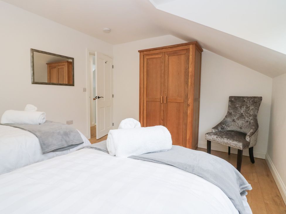 A bedroom with two beds and a wardrobe at Catbells in Windermere
