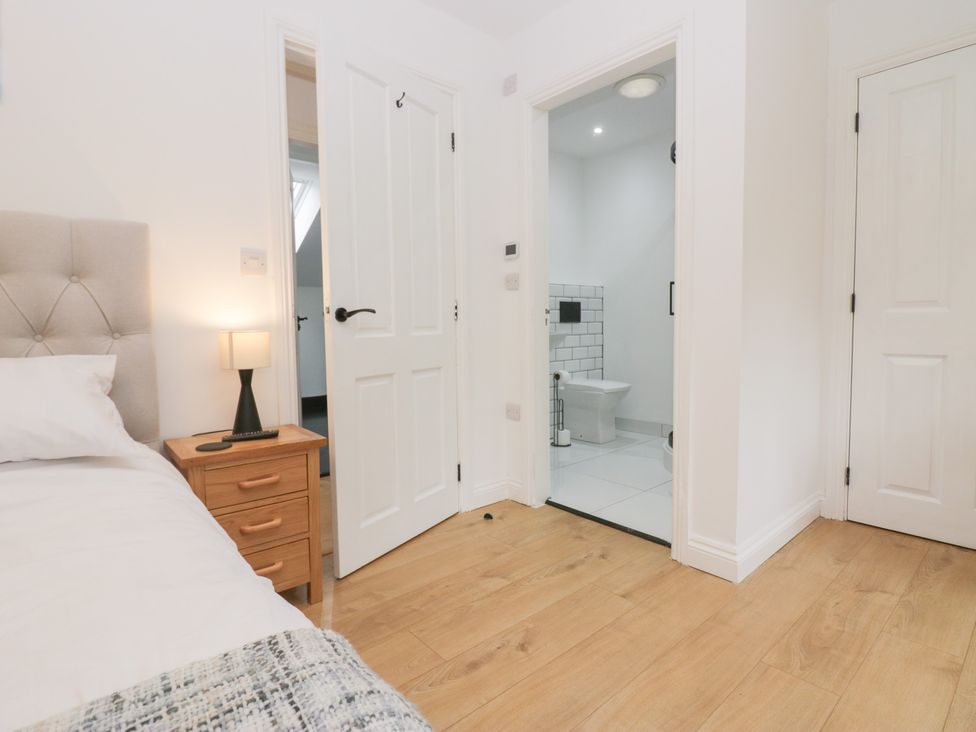 A bedroom with a bed and doorway leading to a bathroom at Catbells in Windermere