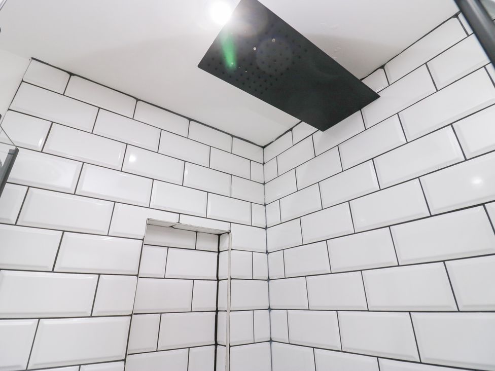 A bathroom with showerhead and tiled walls at Catbells in Windermere
