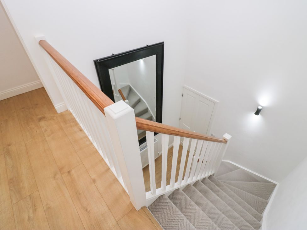 A staircase with a railing and a mirror in the stairway at Catbells in Windermere