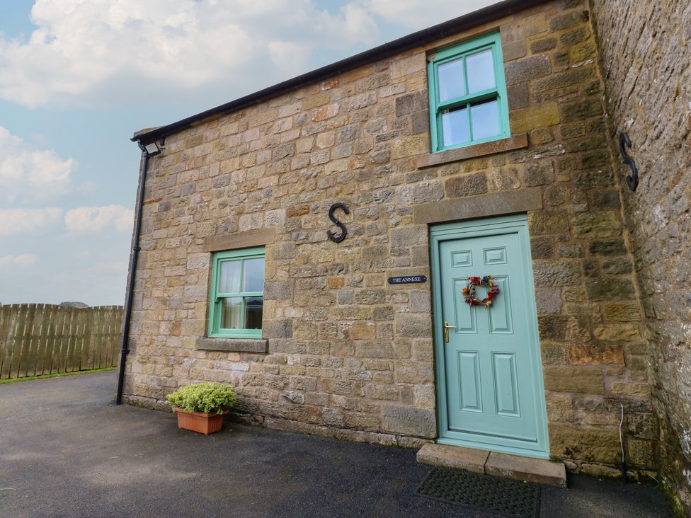 An entrance of a building with stone walls and a green door at The Annex