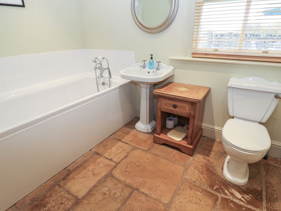 A bathroom with a bathtub, sink, toilet, and wooden cabinet at The Annex in 