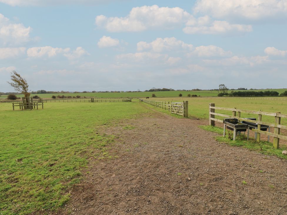 An outdoor view of a field with a gravel path and wooden fence at The Annex in 