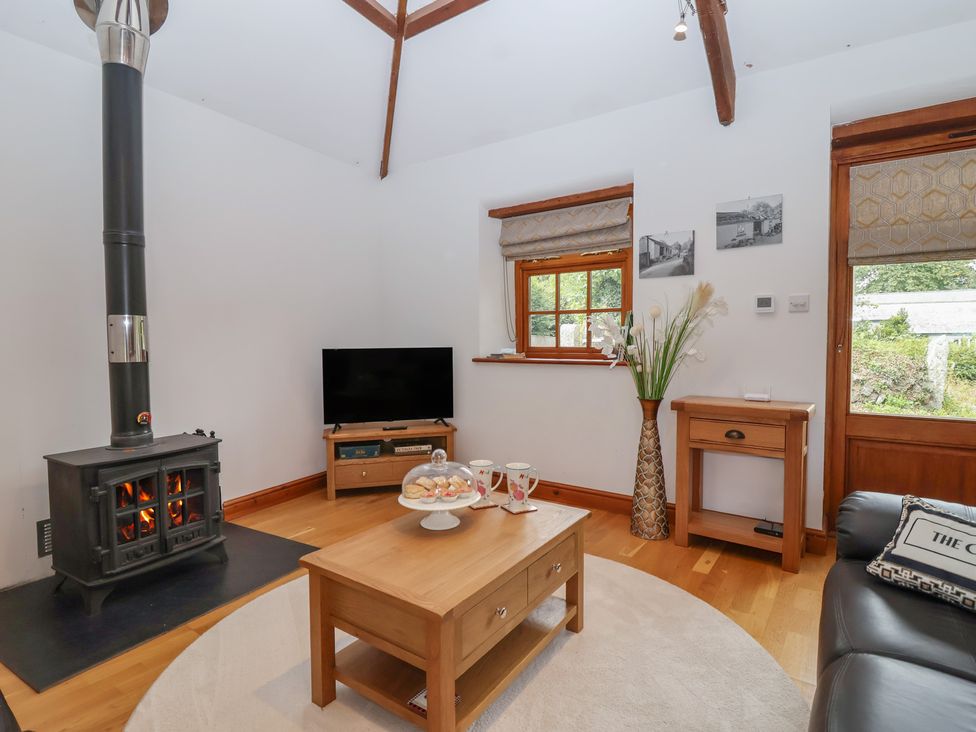 A living room with a stove and television at The Coach House in Tavistock