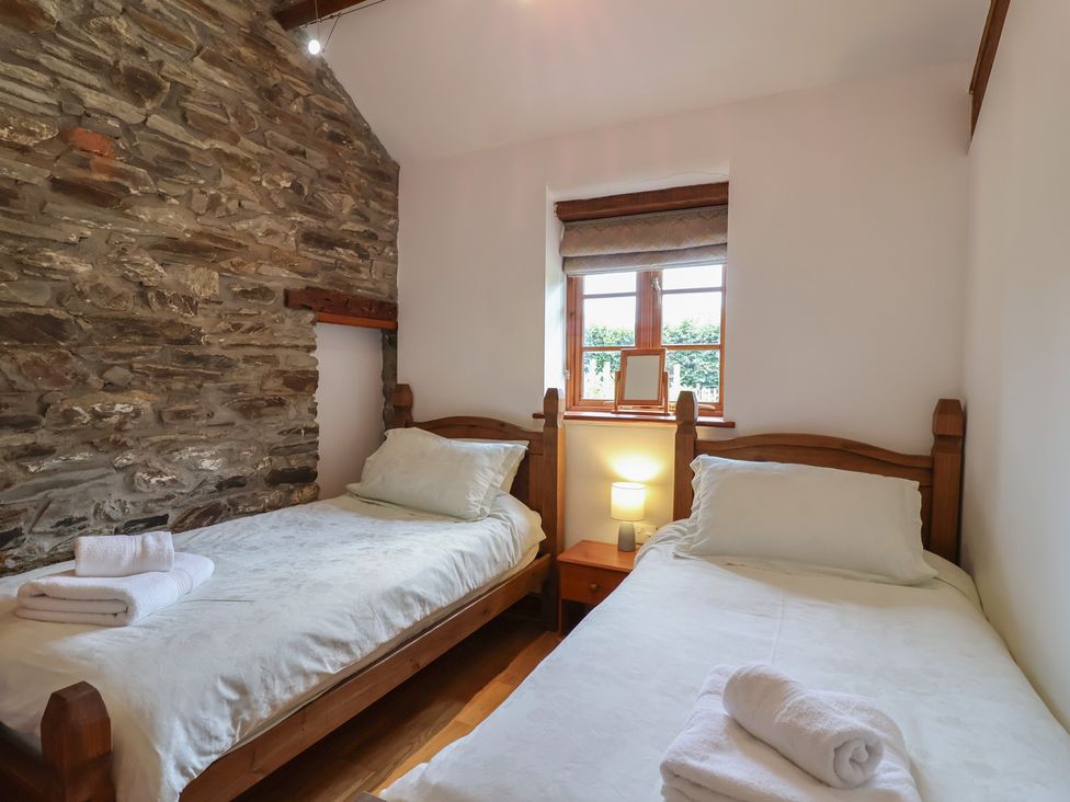 A bedroom with two beds and a window at The Coach House in Tavistock