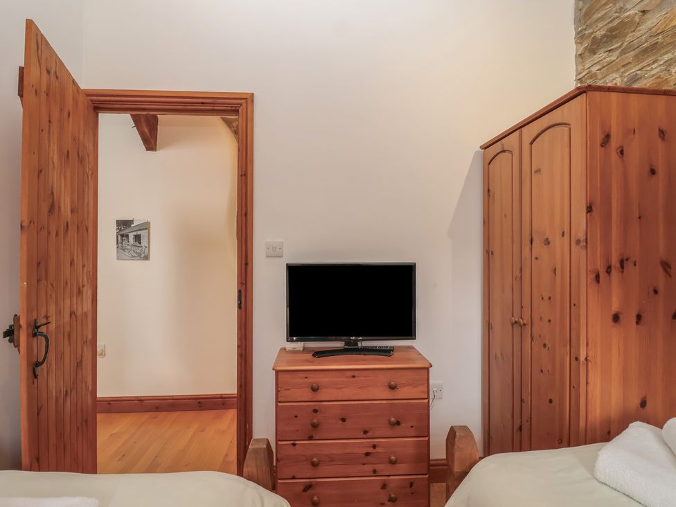 A bedroom with a television and wooden furniture at The Coach House in Tavistock