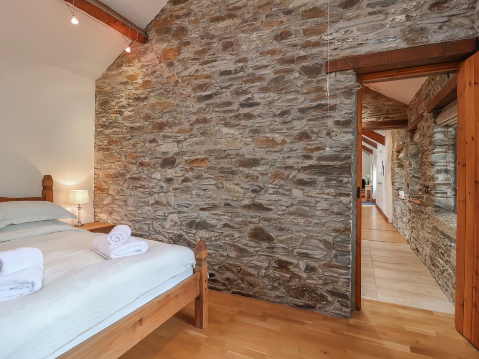 A bedroom with a bed and a doorway at The Coach House in Tavistock