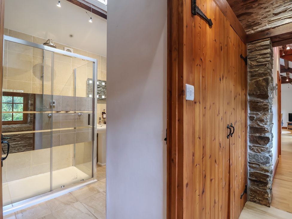 A bathroom with a shower stall and wooden door at The Coach House in Tavistock