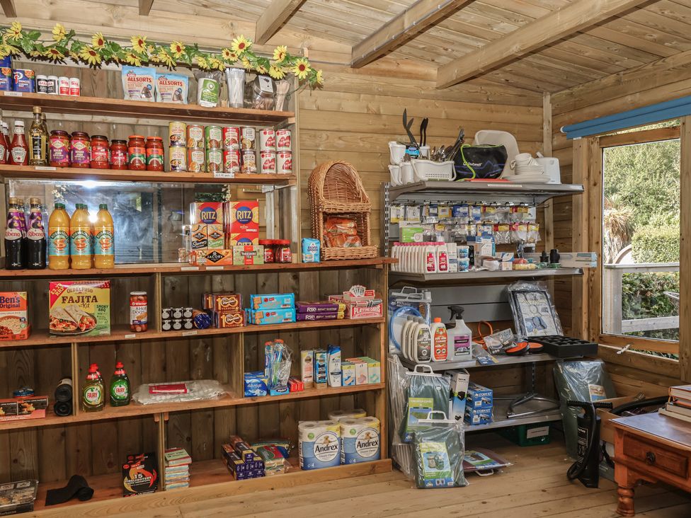 A shed interior with shelves of groceries and household items at The Coach House in Tavistock