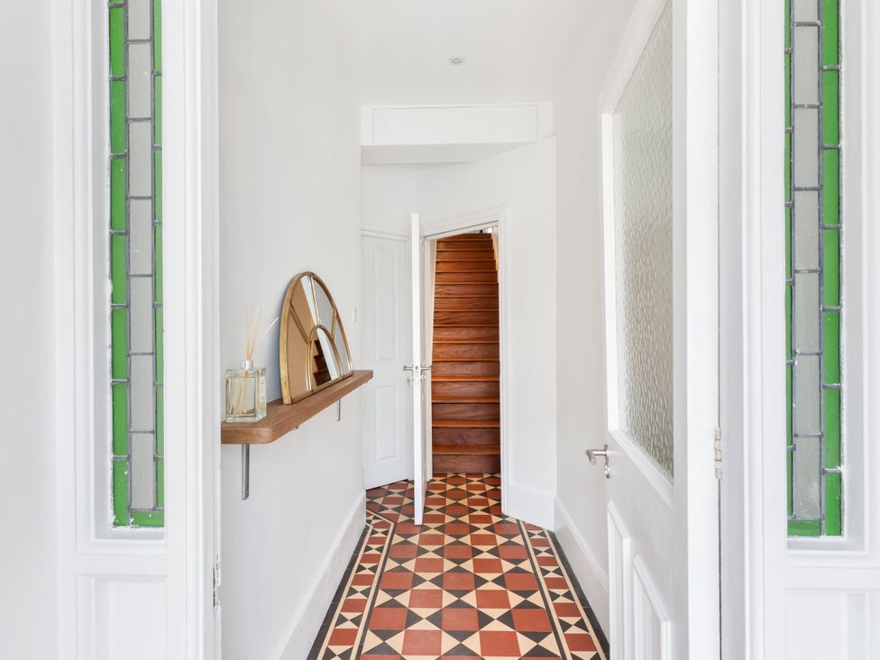 A hallway with a staircase and mirror at The Sundial in St Austell