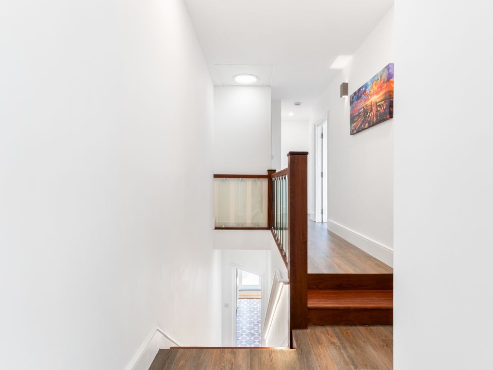 A hallway with stairs and a painting at The Sundial in St Austell