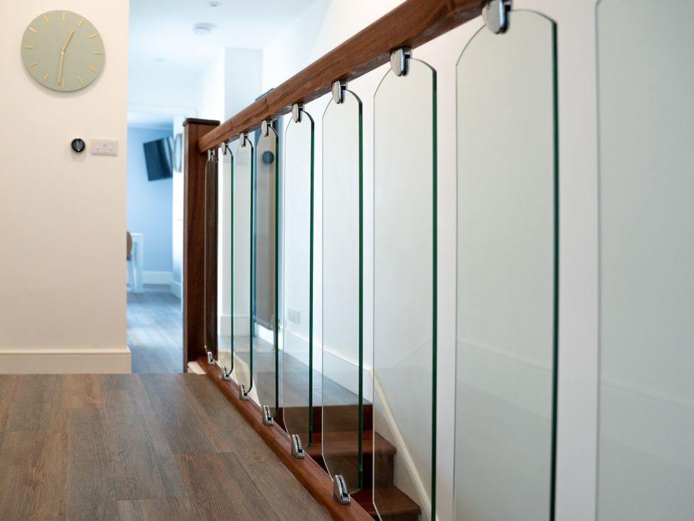A hallway with glass railing and wooden handrail at The Sundial in St Austell