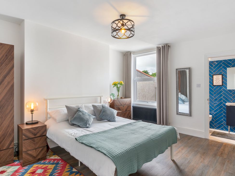 A bedroom with a bed and nightstand with lamp at The Sundial in St Austell