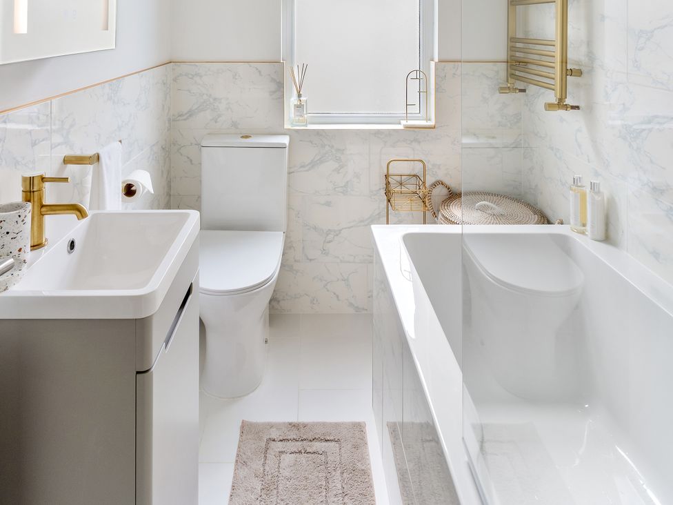 A bathroom with a bathtub, toilet, sink and towel rack at The Sundial in St Austell