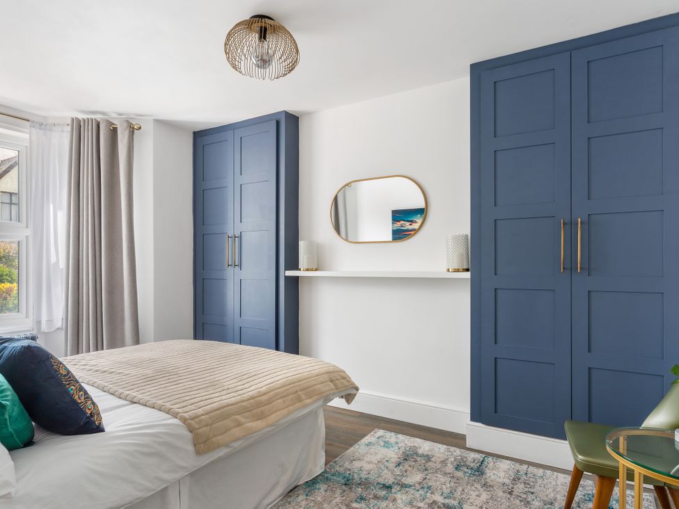 A bedroom with a bed and wardrobe at The Sundial in St Austell